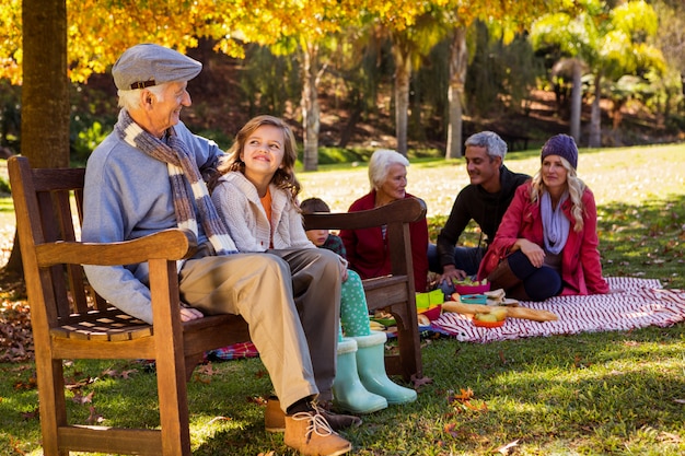 Picnic familiar y el abuelo riéndose con su nieta en un banco