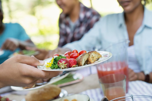 Foto un picnic familiar en un bosque sombreado adultos y niños sentados en una mesa