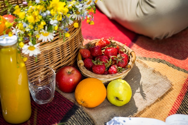 Picnic en el jugo de hierba un ramo de flores silvestres frutasPicnic en el parque en el céspedcomida saludable y accesoriosPicnic Grass Summer Time Rest