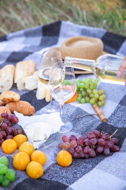 Picnic en la naturaleza, una niña y un hombre sostienen vasos en sus manos con vino. Enfoque selectivo