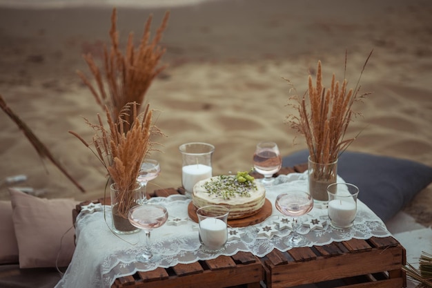 Picnic por la noche al atardecer en la orilla arenosa del mar o decoración oceánica en estilo bohemio y rústico