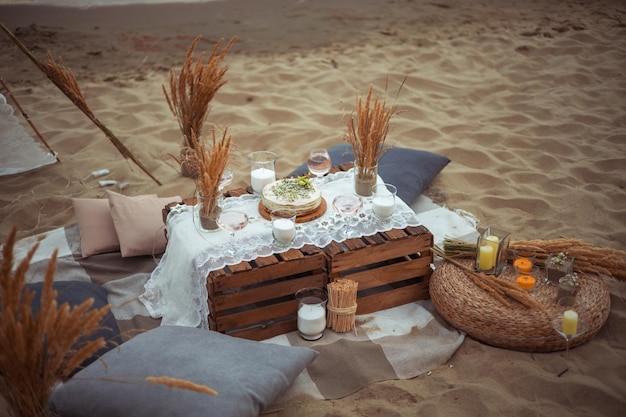 Picnic por la noche al atardecer en la orilla arenosa del mar o decoración oceánica en estilo bohemio y rústico