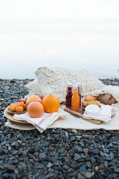 Picnic en la orilla del lago, manta con cesta, fruta y zumo