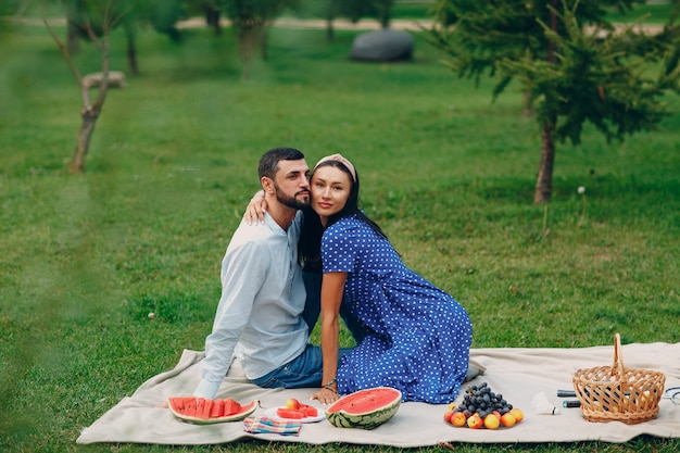 Picnic de pareja de hombre y mujer adulta joven en el prado de hierba verde en el parque.