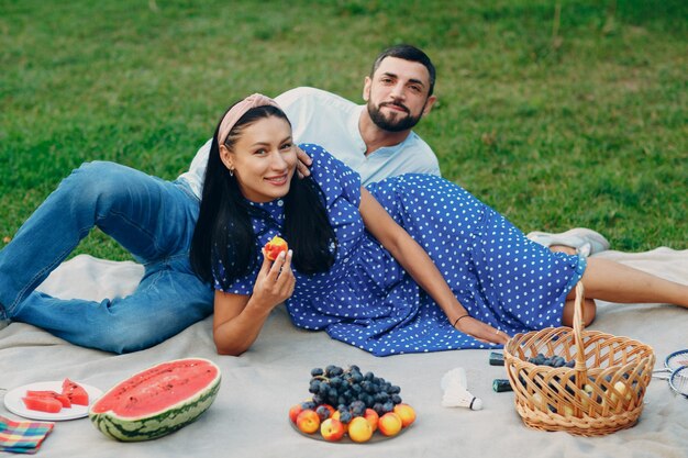 Picnic de pareja de hombre y mujer adulta joven en el prado de hierba verde en el parque.