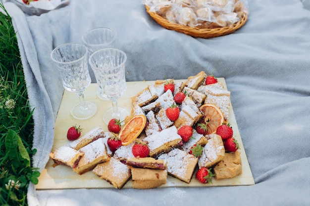 Picnic en el parque con deliciosos pasteles y humor de fresas cerca de la comida