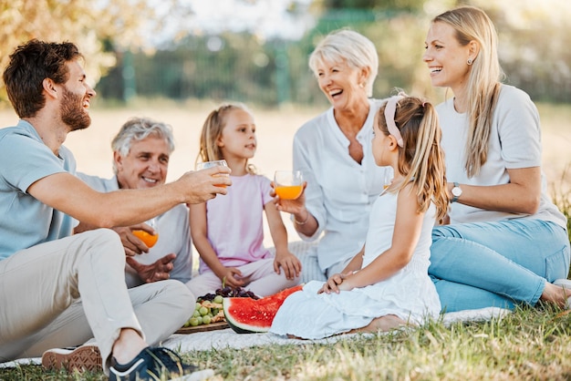 Picnic en el parque riendo y niños de la familia padres y abuelos bebiendo jugo de naranja naturaleza y broma divertida Abuelo del campo de hierba y relajarse abuela mayor padre o madre vínculo con los niños del jardín