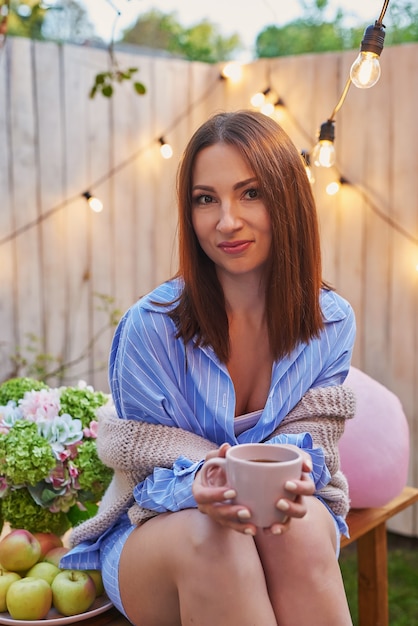 Picnic en el patio trasero. Celebracion. Vida feliz. Tarjeta de felicitación de cumpleaños feliz. Mujer con taza de café o té. Hermosa mujer joven. Dia de la mujer. Jardín de verano