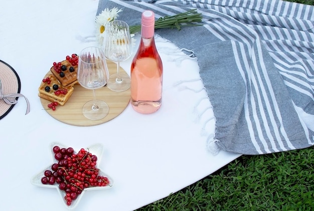 Picnic romántico de verano en el parque sobre la hierba Champán y dos copas en plaid blanco Concepto de comida y bebida