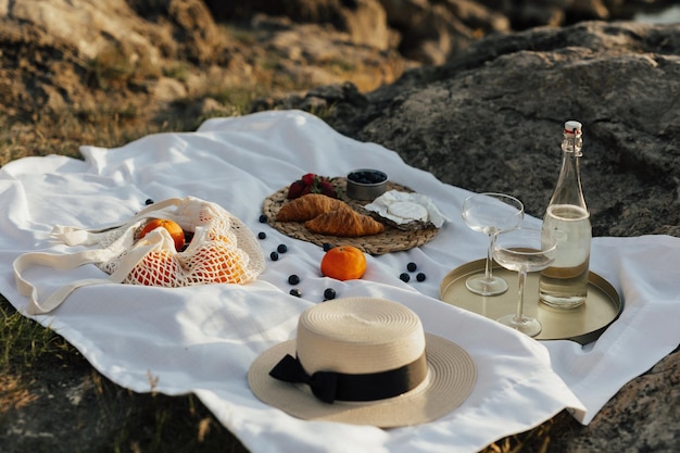 Un picnic con sombrero y una bolsa de comida sobre una manta.