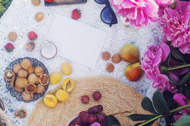 Picnic de verano al aire libre al estilo francés en un jardín de peonías con croissant de almendras y frutas frescas