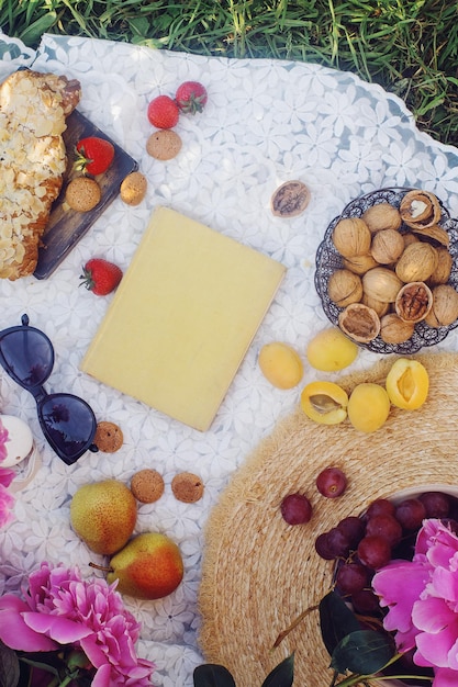 Picnic de verano al aire libre al estilo francés en un jardín de peonías con croissant de almendras y frutas frescas