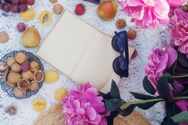 Picnic de verano al aire libre al estilo francés en un jardín de peonías con croissant de almendras y frutas frescas