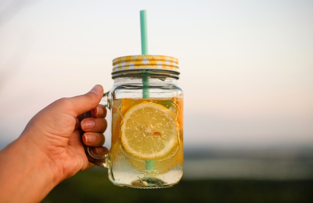 Picnic de verano al aire libre, tarro de bebida de verano con limonada, en la mano