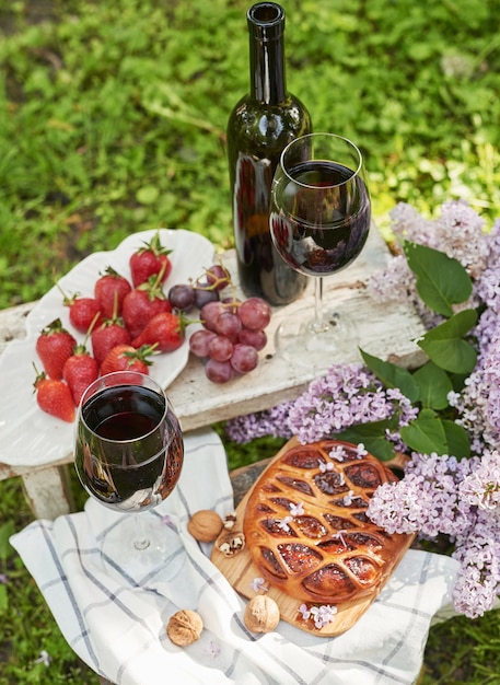 Picnic de verano en el jardín Pastel de vino frutas y flores Bodegón Almuerzo de Pascua y mesa