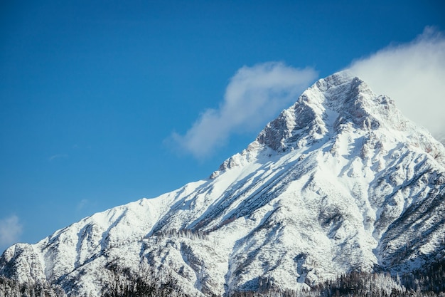 Pico de montanha de neve épico com nuvens na paisagem de inverno alpes áustria