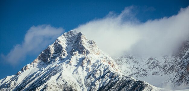 Foto pico de montanha de neve épico com nuvens na paisagem de inverno alpes áustria