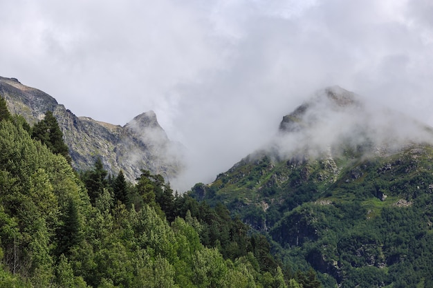 Pico de la montaña con glaciares contra la superficie de las nubes y el cielo