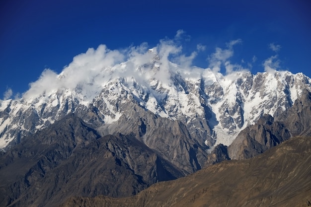 Pico de la montaña Ultar Sar detrás de las nubes. Batura Muztagh, gama Karakoram. Pakistán.