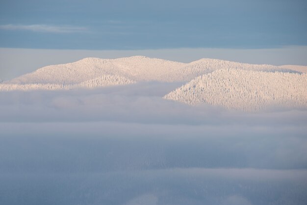 Pico de montañas en la nieve por encima de las nubes