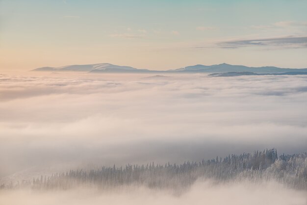 Pico de montañas en la nieve por encima de las nubes