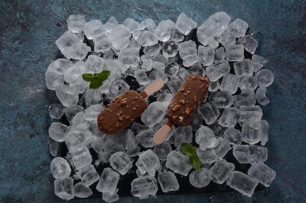 Foto picolé de sorvete de chocolate com amêndoas em um fundo de cubos de gelo