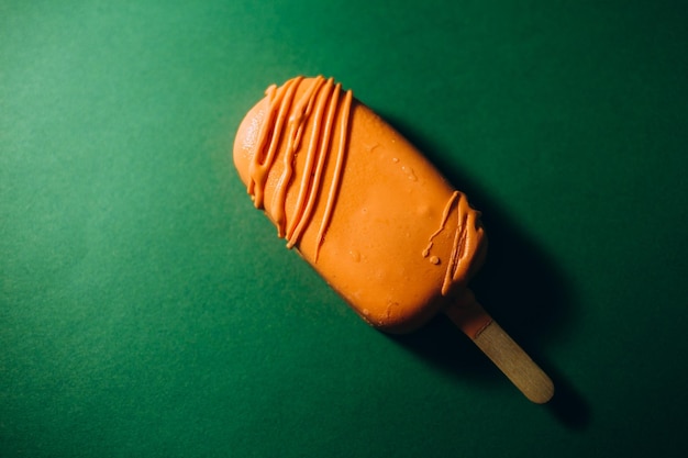 Picolé de sorvete de chocolate com flocos de amêndoa em fundo verde