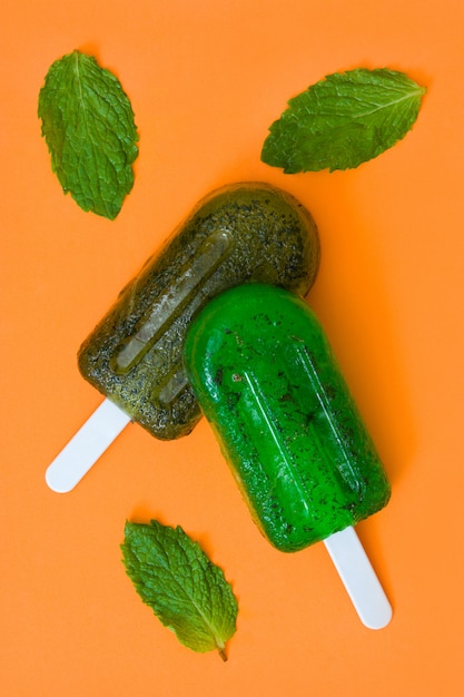 Picolés congelados verdes na mesa laranja Vista superior