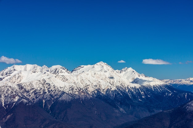 Los picos de las montañas nevadas en el fondo del cielo azul