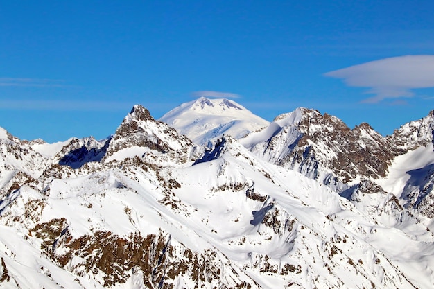 Picos de las montañas nevadas en las nubes cielo azul Cáucaso