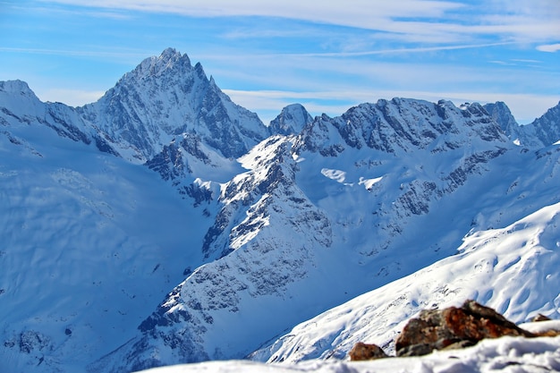 Picos de las montañas nevadas en las nubes cielo azul Cáucaso