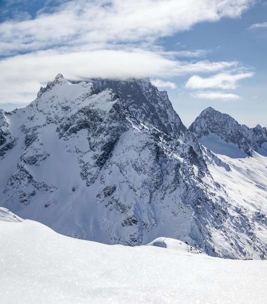 Picos de las montañas nevadas en las nubes cielo azul Cáucaso