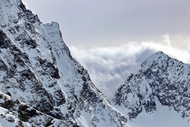 Picos de las montañas nevadas en las nubes cielo azul Cáucaso