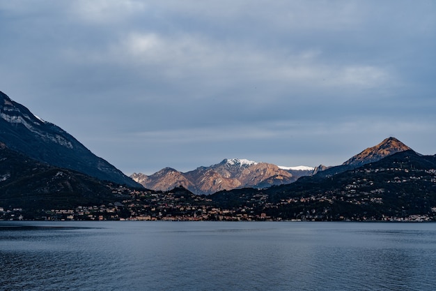 Picos nevados de una cadena montañosa en rayos de sol lago de como italia