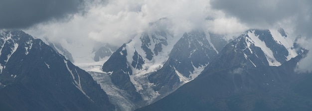 Picos nevados do cenário da montanha nas nuvens panorâmicos