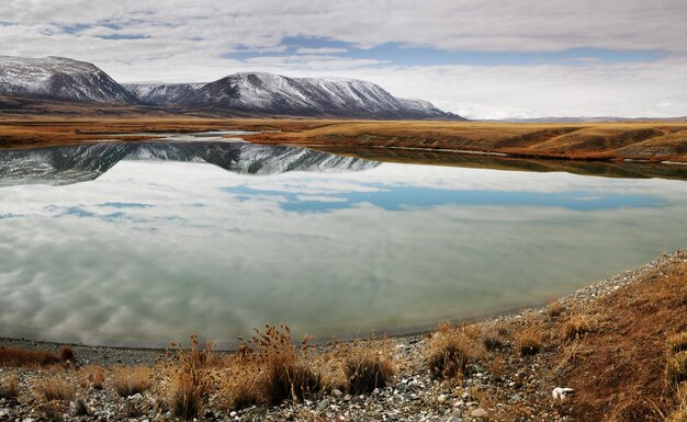 Los picos nevados se reflejan en un lago de montaña ásperos paisajes de la naturaleza del norte