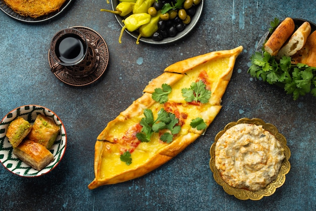 Pide - tradicional pizza turca feita de massa com carne picada, legumes e cobertura de queijo derretido. Prato popular do Oriente Médio servido com petiscos, sobremesas e chá turco. Vista do topo