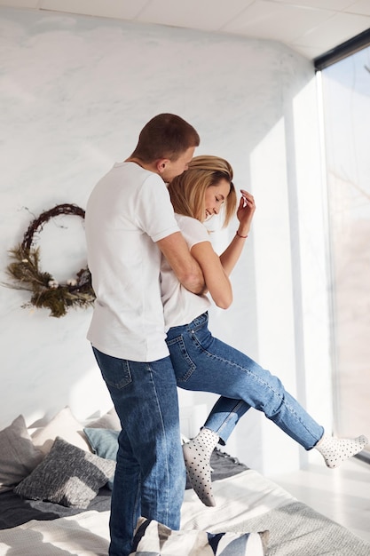 De pie y abrazándose en la cama Joven pareja encantadora juntos en casa pasando el fin de semana y las vacaciones juntos