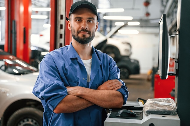 De pie con los brazos cruzados Mecánico de automóviles trabajando en el garaje Servicio de reparación