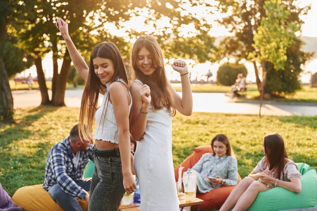 Foto de pie y divirtiéndose grupo de jóvenes tienen una fiesta en el parque durante el día de verano