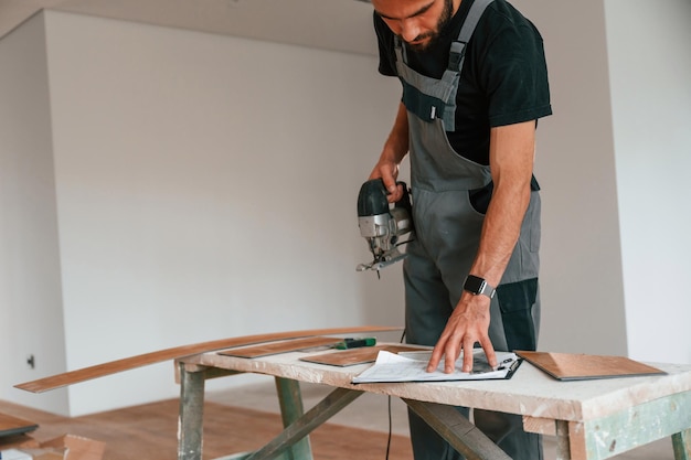 De pie junto a la mesa con el rompecabezas El hombre está instalando un nuevo piso de madera laminada