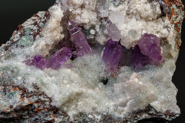 piedra mineral macro ametista en la roca en un fondo negro de primer plano