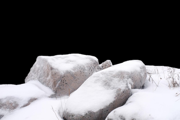 Piedra natural en la nieve aislada sobre fondo negro Foto de alta calidad