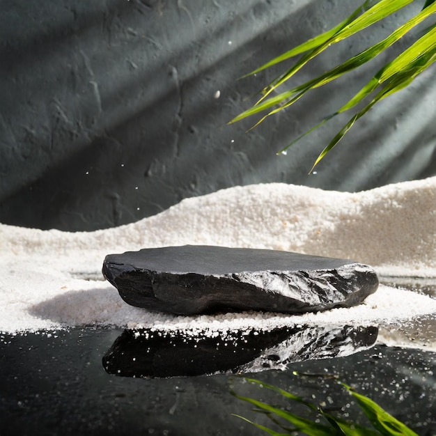 Foto piedra negra plana para la maqueta de la etapa del producto con arena blanca y reflejo de agua