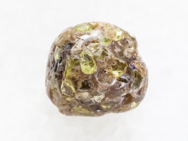 Piedra preciosa de peridoto caído sobre mármol blanco