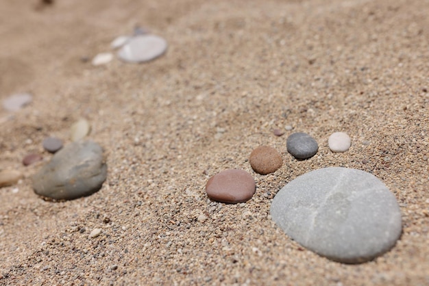 Piedra puesta en forma de pie humano en la arena playa de arena de la costa de un día caluroso de verano