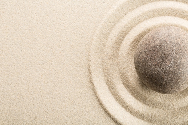 Foto piedra zen en la arena sobre fondo claro