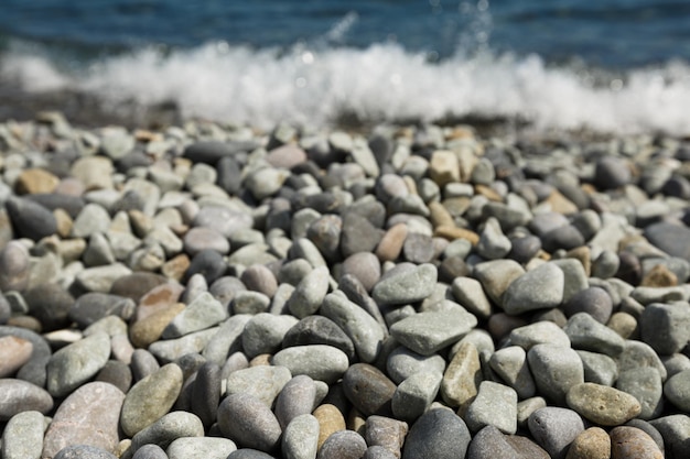 Piedras de canto rodado y con marea de mar en el fondo