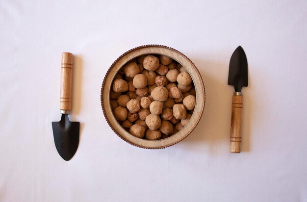 Piedras comestibles de arcilla de caramelo sobre un plato redondo de madera con pequeñas palas de jardín sobre un fondo blanco