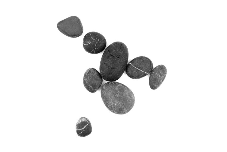 Piedras de guijarros lisos aislados en la vista superior de fondo blanco
